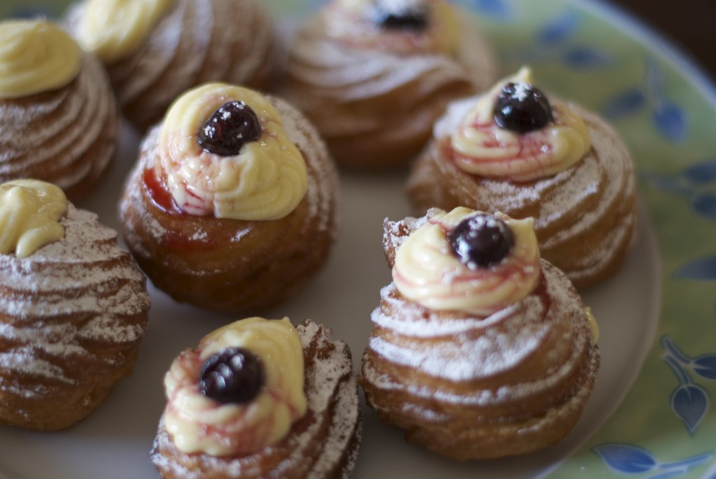 8 round pastries on a plate, topped with cream and a berry